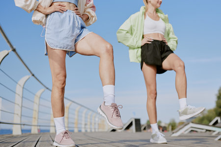 Low angle shot of unrecognizable women warming up their joints before open air workoutの写真素材
