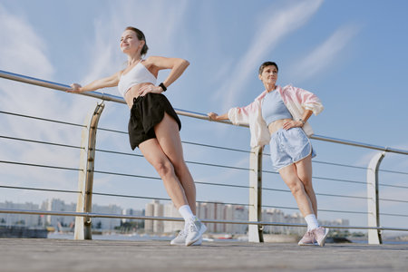 Two Caucasian women doing sport together and enjoying good weather and fresh air on waterfrontの写真素材