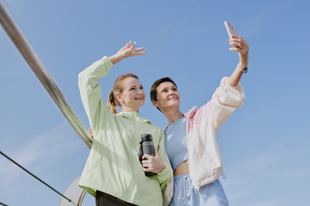 Low angle shot of senior mom taking selfie with her young adult daughter after open air trainの写真素材
