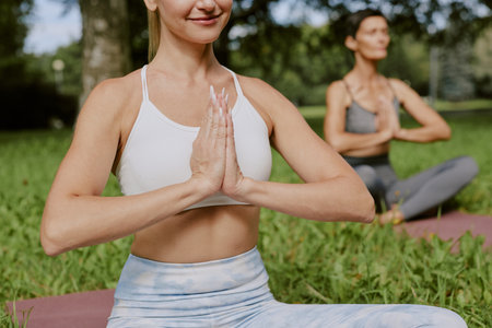 Medium closeup of unrecognizable women of different age sitting in lotus pose and enjoying harmonyの写真素材