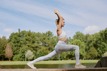 Side view shot of young blonde woman in good shape holding high lunge position