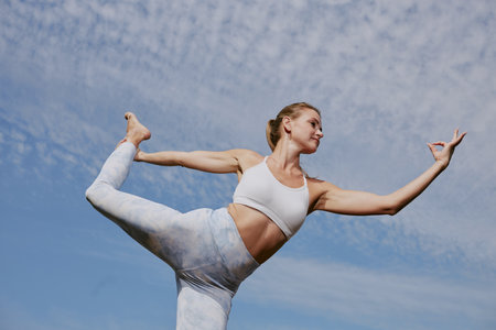 Low angle shot of confident and strong woman holding dancer pose under open skyの写真素材