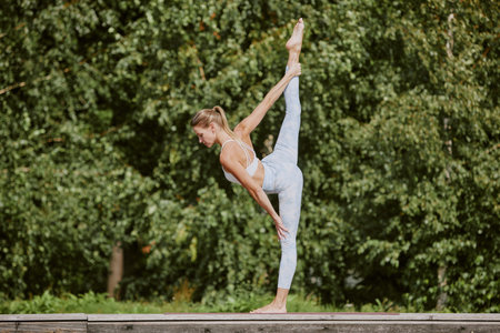 Young blonde woman holding standing splits, she improving her flexibility and body balanceの写真素材
