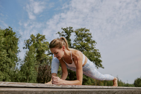 Low angle shot of young Caucasian blonde woman stretching her leg muscles before main workout in open airの写真素材
