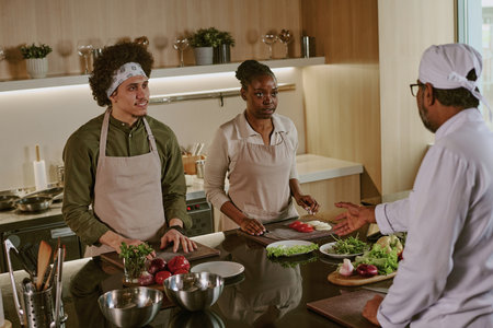 High angle shot of unrecognizable chef in white uniform giving orders to his cook who standing next to kitchen counterの写真素材