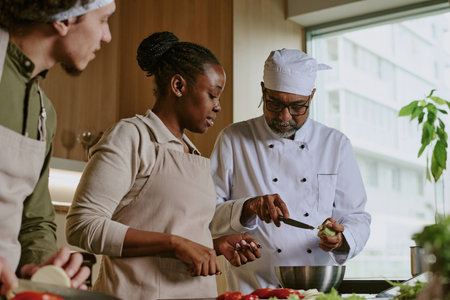Low angle shot of professional chef showing peeling skills while interns watching himの写真素材