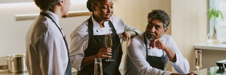 Website banner of young African American cook holding glass of champagne and saying toast to her male colleaguesの写真素材