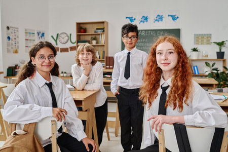 Group of diverse gen alpha boys and girls wearing school uniform posing for portrait in modern classroomの写真素材