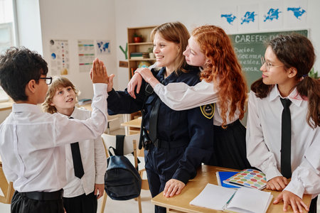 Female police officer and teenagers hugging and doing high five after career guidance class at schoolの写真素材