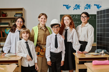 Group of young teacher, female engineer and gen alpha students posing for portrait in classroom on vocational guidance dayの写真素材