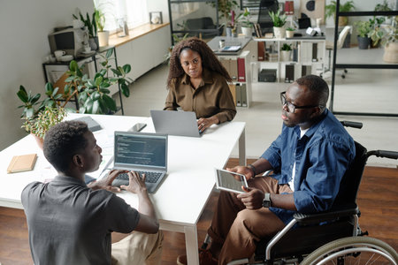 High angle shot of African American developer team discussing startup while coding in modern officeの写真素材