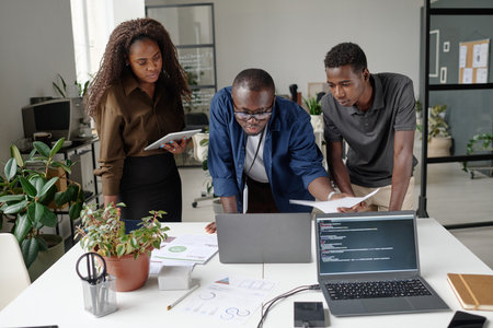 African American team of young and successful developers discussing and creating new codes in white officeの写真素材