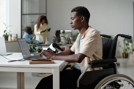 Side view shot of African American programmer with disability coding in spacious officeの写真素材