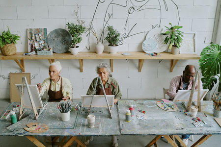 High angle shot of biracial retired people enjoying hobby in retro studio with plants and minimalist decorの写真素材