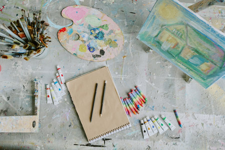 Top down shot of old dirty table with empty sketchbook and drawing equipment