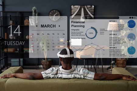 Rear view of unrecognizable Black man wearing VR headset sitting relaxed on sofa in living room...
