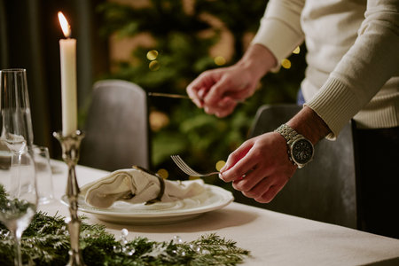 Medium close up of unrecognizable male hands holding polished silver fork and knife while serving X-mas tableの写真素材