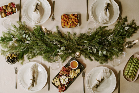 Top down shot of table with polished crystal glasses and crockery, plates with appetizers and...