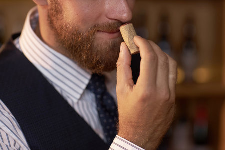 Medium close up of unrecognizable sommelier smelling wine cork while holding it in handの写真素材