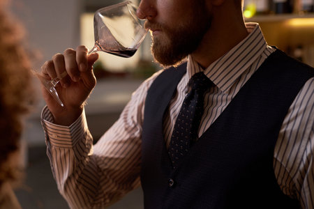 Medium close up of unrecognizable man in smart clothes holding crystal glass with red wine, he expertizing aromaの写真素材