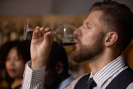 Medium close up of Caucasian professional sommelier takin first sip of red wine during degustation in wine cellarの写真素材