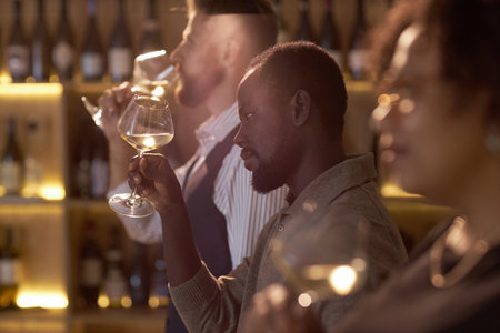 African American sommelier estimating wine color while attending sommelier course in wine cellar