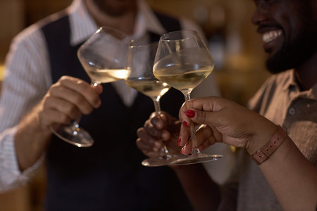 Medium close up of unrecognizable sommeliers clinking glasses with white wineの写真素材