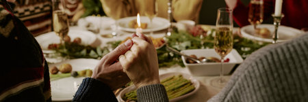 Website banner with unrecognizable people sitting at festive table and holding each other hands while prayingの写真素材