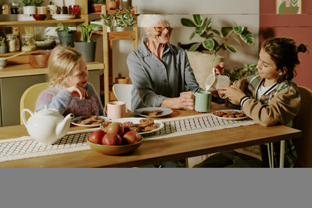 Elderly woman spending quality time with grandchildren at breakfast table. Sharing tea and warm...