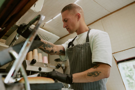 Low angle shot of focused chef frying hot dog buns on grill in food truckの写真素材
