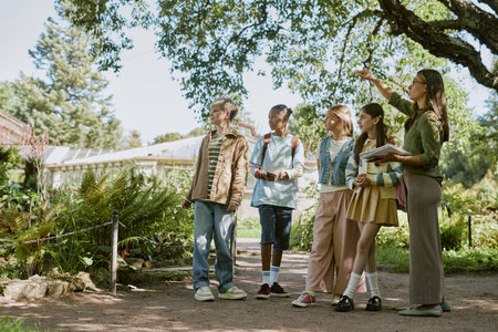 Young female botanical garden worker showing rare plants to group of teen students during tour, copy spaceの写真素材