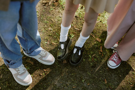 High angle view of legs of unrecognizable teen boy and girls standing outdoorsの写真素材