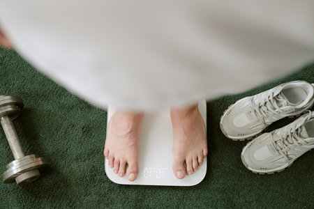 Close-up of feet stepping on weight scale after workout showing commitment to fitness routine....