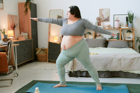 Person performing yoga balancing pose in cozy, well-decorated bedroom, focusing on a peaceful and healthy lifestyleの写真素材
