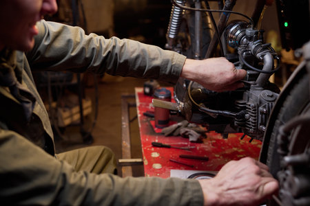Young adult man assembling and repairing custom motorcycle engine in workshop, focusing on...