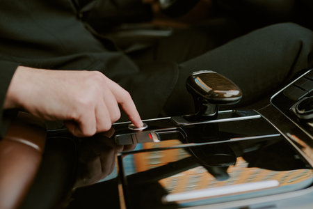 Caucasian young adult man pressing button on modern car center console, hand and part of arm...