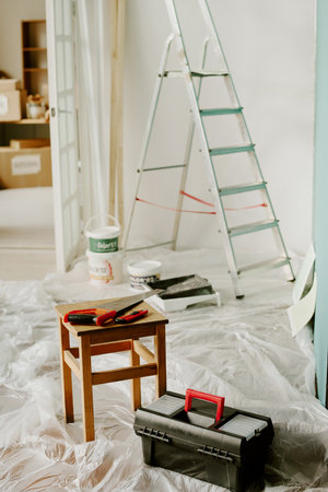 Renovating new home, painting walls and preparing space for moving, plastic sheets covering floor,...