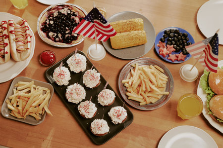 High angle shot of famous American food served on plates on wooden table, table decorated with American flag as symbol of holidayの写真素材