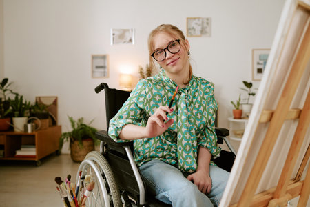 Portrait of Caucasian young adult woman with disability sitting in wheelchair smiling at camera...
