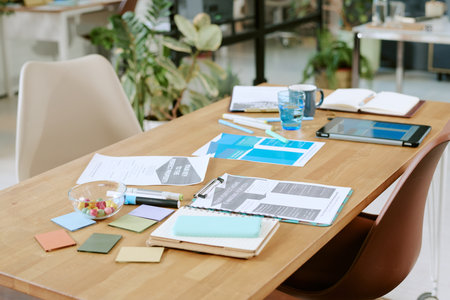 Modern office workspace showing documents, digital tablet, open notebook, colorful sticky notes and...