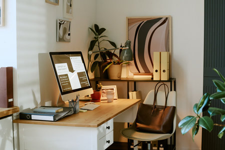 Modern home office workspace featuring desktop computer displaying charts and documents, organized...