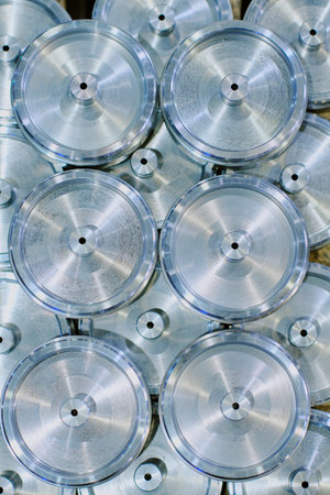 Stacked metal discs arranged in organized pattern, showing shiny machined surfaces with concentric...