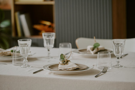 Elegant table setting featuring neatly arranged plates, glasses, cutlery, and folded napkins with...