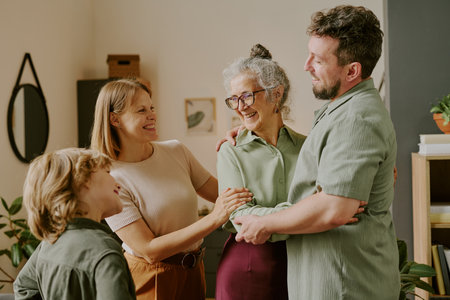 Caucasian middle aged woman, her husband and child smiling and embracing each other in home setting, showing family connectionの写真素材