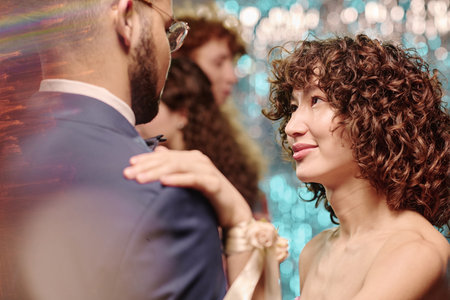 Teen girl gazing at boy while dancing together at formal event, background showing other young adults interacting, festive atmosphere impliedの写真素材