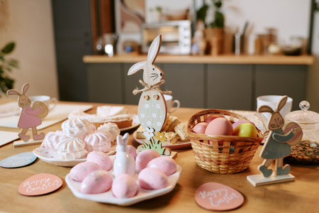 Easter themed table featuring wooden bunny decorations, basket filled with colorful eggs, meringue...