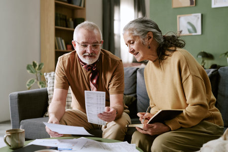 Senior Caucasian man and senior Caucasian woman reviewing financial documents together at home, man...