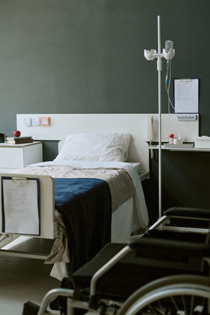 Hospital room standing prepared for patient care in medical facility, showing bed, wheelchair, IV stand, recovery setting. Useful for healthcare services, veteran treatment campaigns