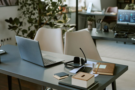 Empty modern call center office desk with laptop, headset, and notebook. Scene represents remote support, customer service, and telemarketing workspace, suitable for corporate communication