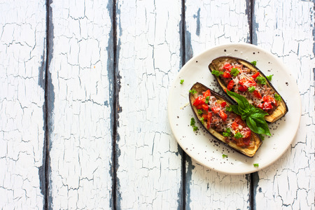 Stuffed eggplants with mince and vegetables in white plate over wood grunge backgroundの写真素材